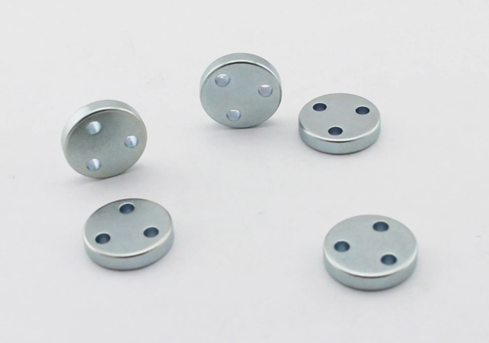 Physical image of small round galvanized magnet with 3 small holes;